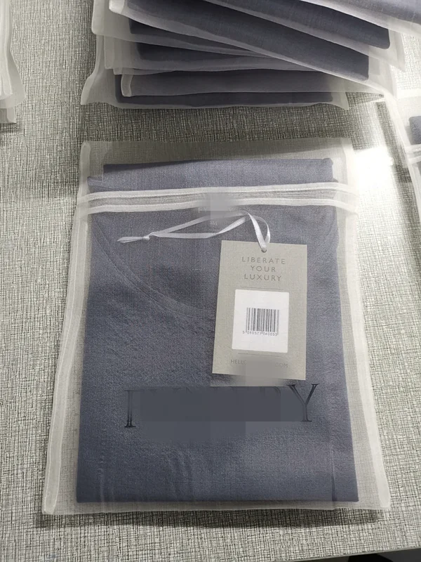 Folded silk garment packed in a branded mesh zipper bag with tags