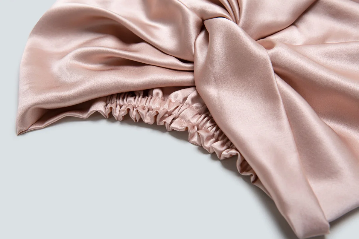 Close-up of the gathered elastic opening on a blush silk bonnet
