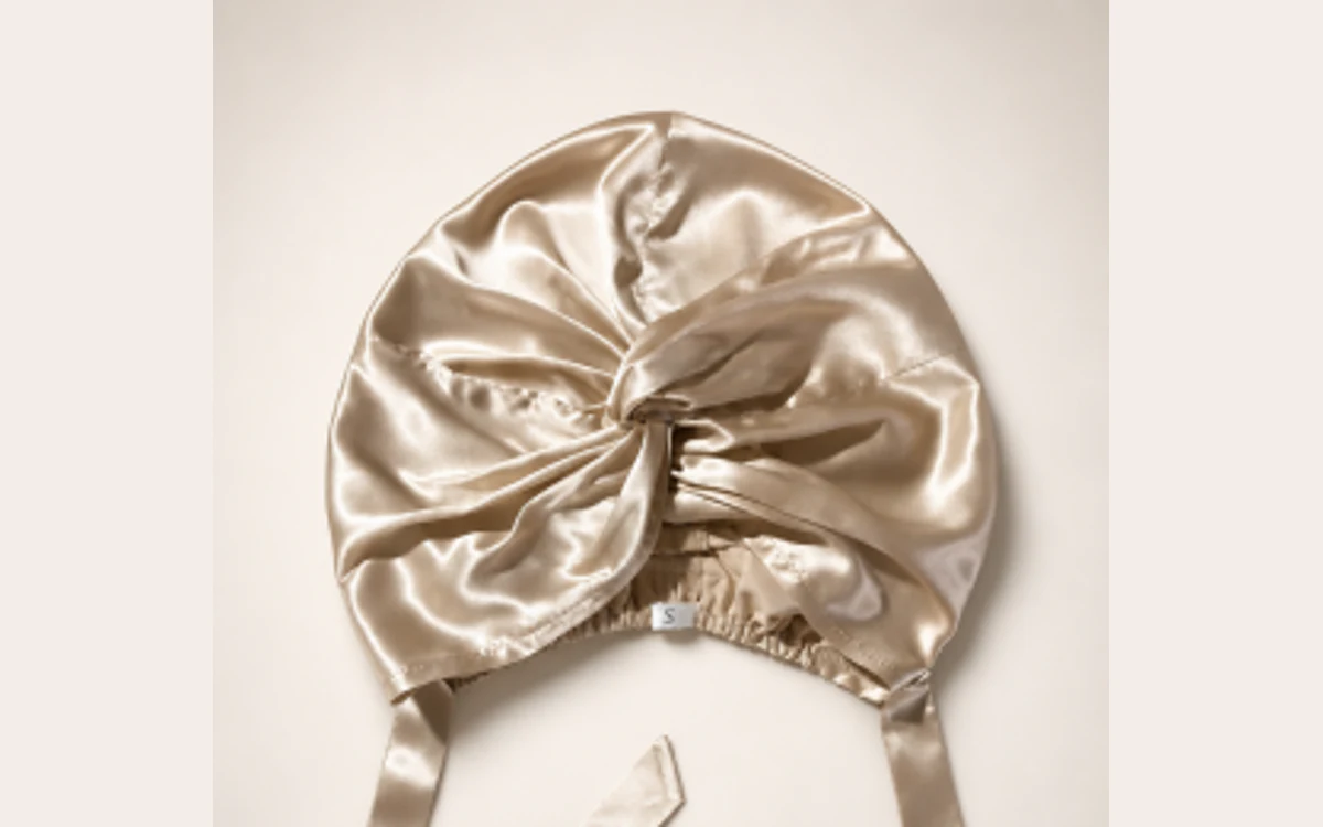 Close-up of a champagne silk tie bonnet shown flat