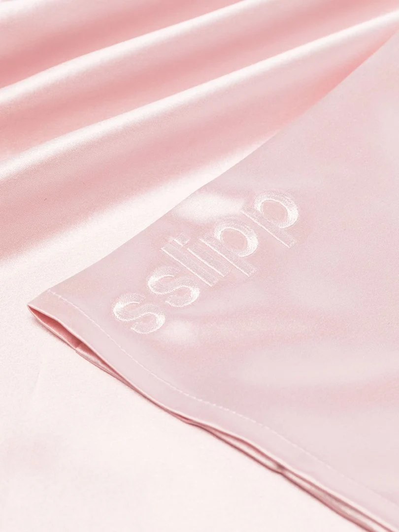Tone-on-tone embroidered logo on a pink silk pillowcase edge