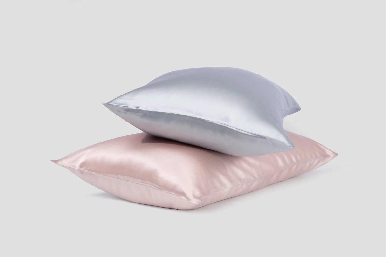 Silver and blush silk pillowcases stacked together