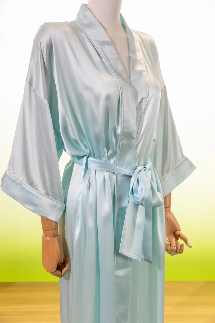 Close view of a light aqua silk robe showing its smooth fabric, collar, cuffs and belt