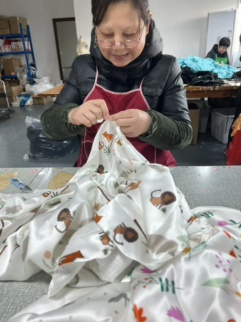 Craftsperson completing hand finishing on a printed silk garment