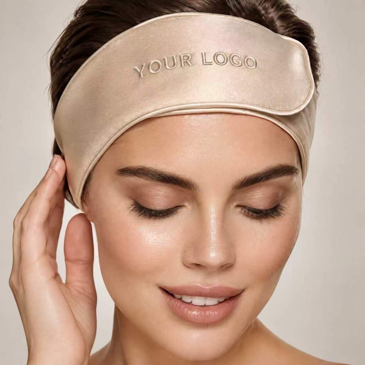 Embroidered logo on a champagne silk headband worn by a model