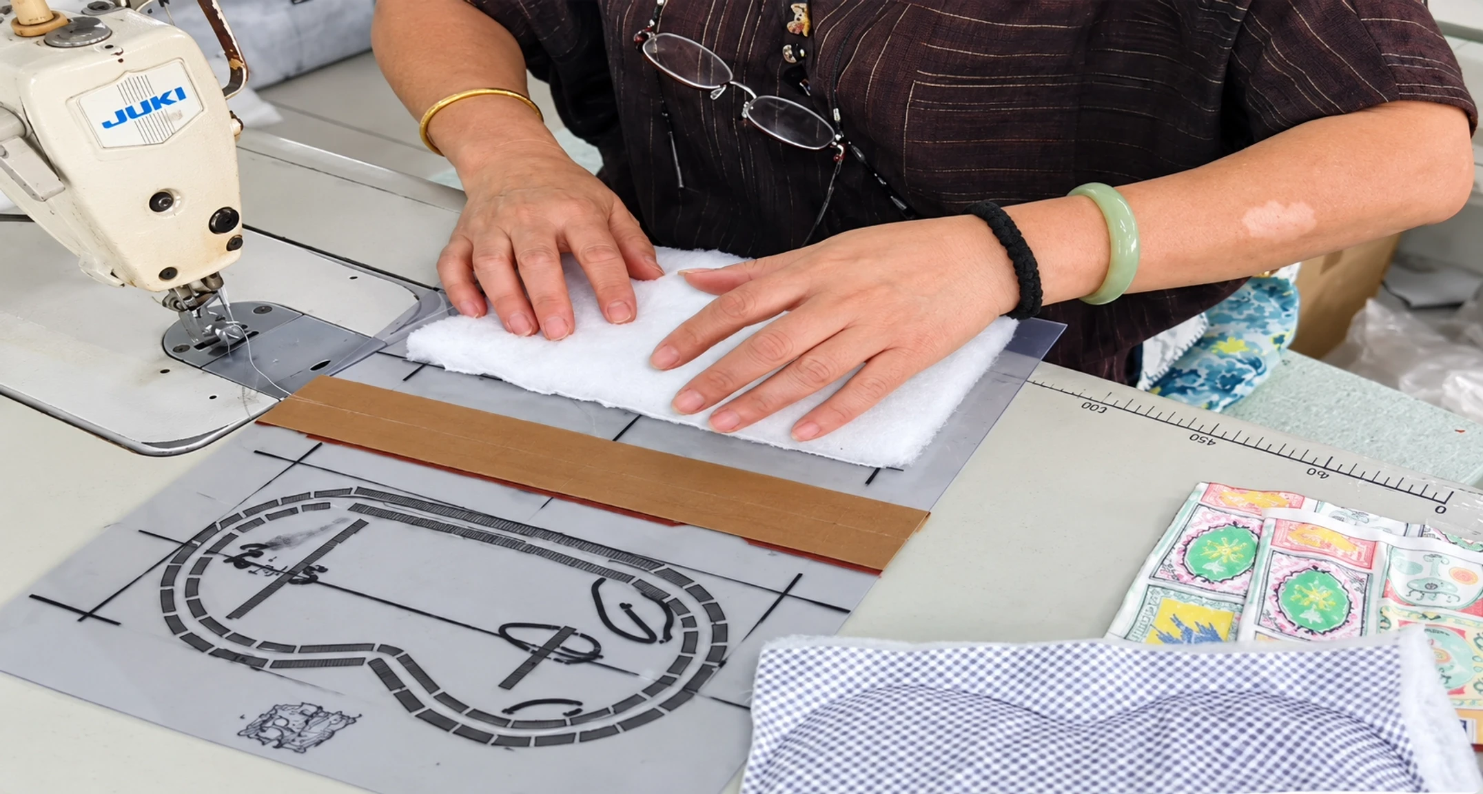 Factory worker aligning eye mask fabric and padding with an acrylic pattern template