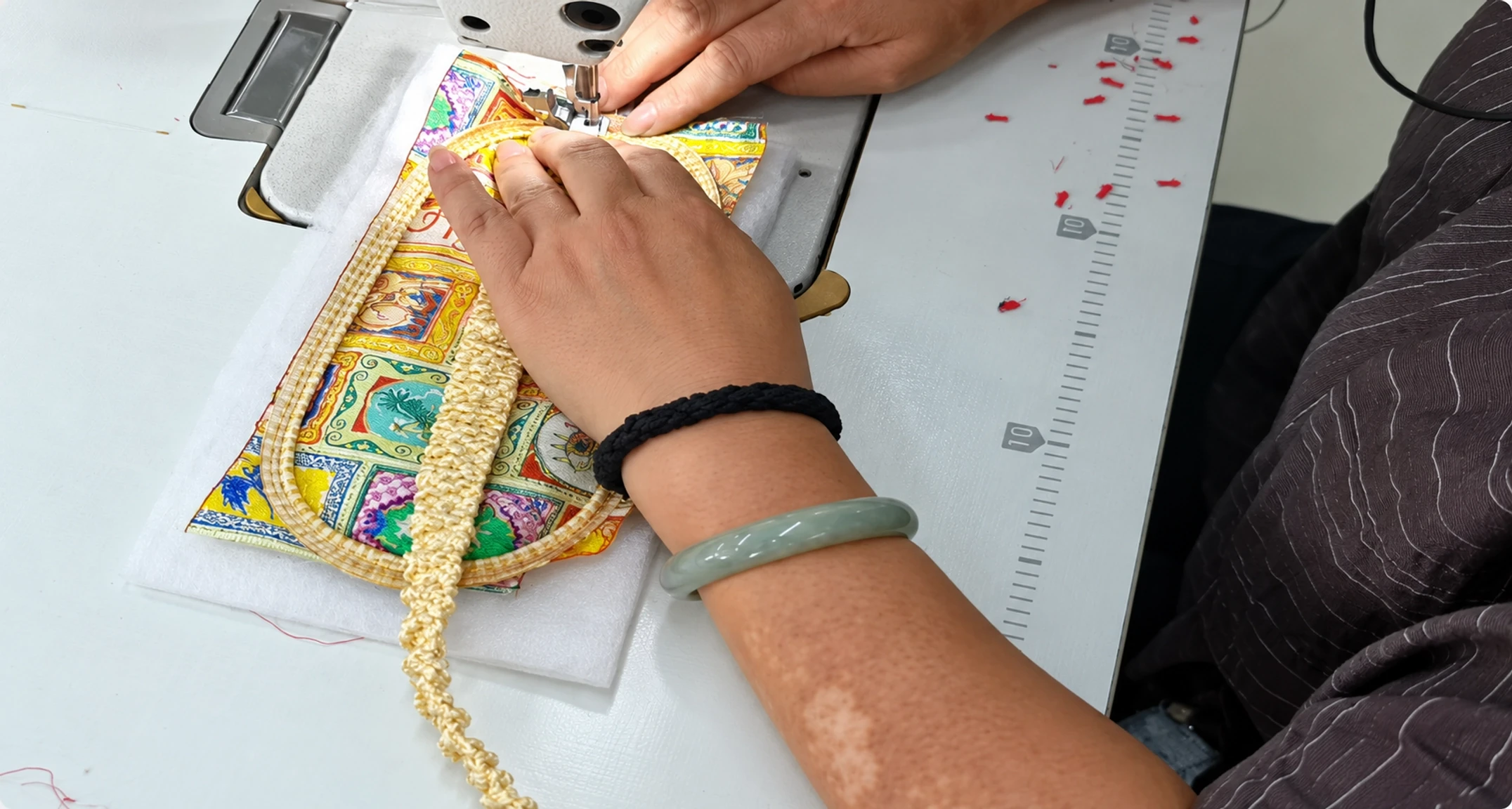 Factory worker securing a silk-covered elastic strap to a printed eye mask